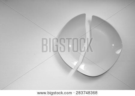 Cracked White Plate On The White Background. Two Pieces Of The Broken Dish