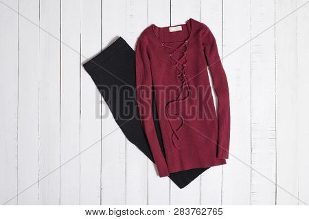 Clothes And Accessories. Black Midi Skirt And Red Sweater With Lacing On White Wooden Floor Planks. 