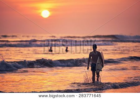 Surfer St Sunset. Young Man Holding Surfboard And Walking To Sea. Matara, Sri Lanka.