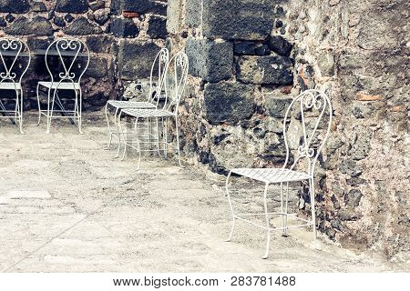 White Metall Chairs In The Yard Of Castle Acicastello, Acitrezza, Catania, Sicily, Italy