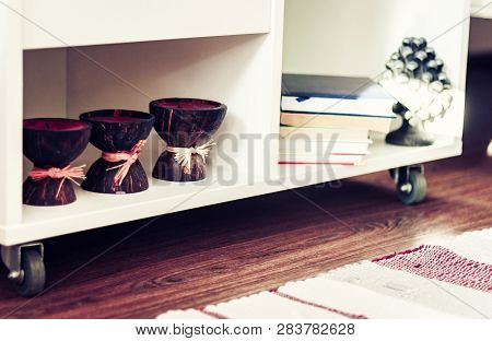 White Nightstand With Candles And Books, Next To A Multi-colored Rug