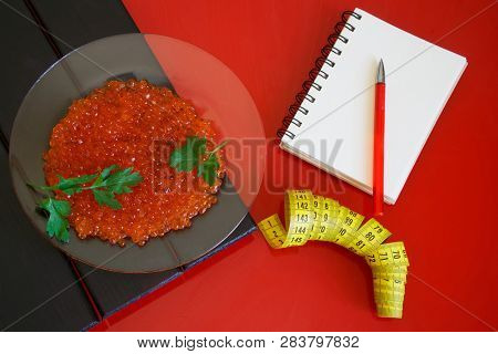 Red Caviar In A Transparent Plate Next To A Notepad And A Tape Measure. Counting And Recording The A