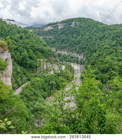 Skybridge Suspension Bridge Over A Gorge Over An Abyss With A River And Serpentine Road On A Cloudy 