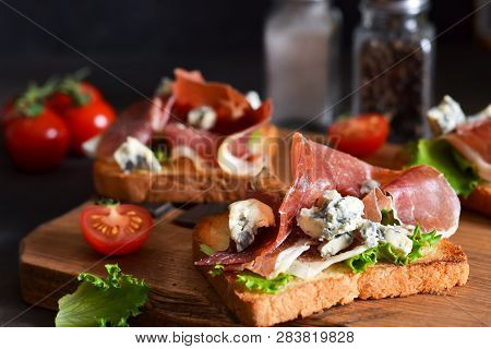 Bruschetta With Prosciutto, Salad Frieze And Cheese On The Kitchen Table. Snack.