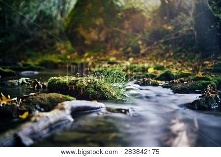 Long Exposure Of A River Creek With A Small Waterfall. Sunset And Strong Detail Bokeh View. Blue Cal