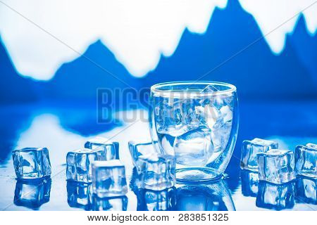Double Wall Glass Of Clear Water On A Cold Background With Ice Cubes And Mountain Peaks. Drinking Fr