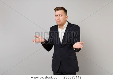 Perplexed Young Business Man In Classic Black Suit, White Shirt Shrugging Shoulders, Spreading Hands