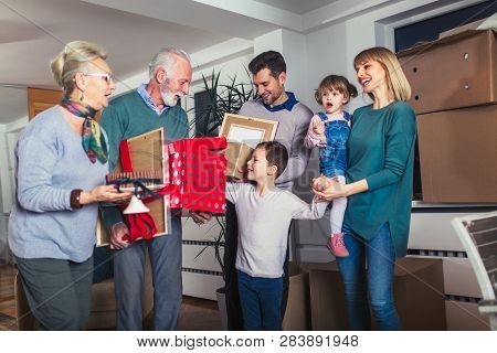 Grandmother And Grandfather Bring A Gift For Moving Into A New Apartment To Their Children