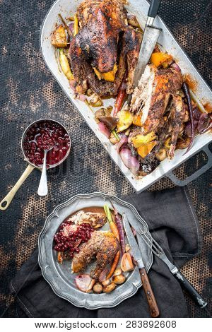Traditional barbecue pheasant with vegetable and cranberry sauce as top view in a stewpot and on a plate 
