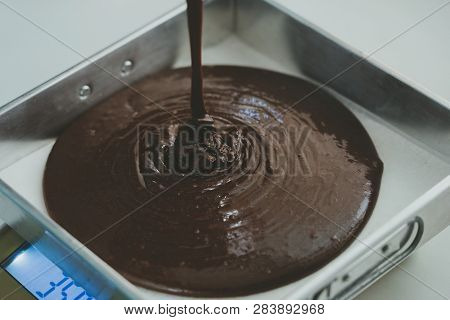 Dark Brown Chocolate Cream Is Poured On A Tray For Baking In A Heat Oven. This Cream Is The Raw Mate
