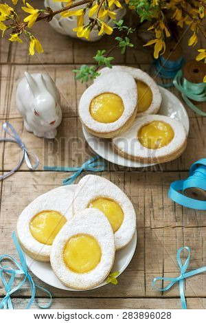 Easter Composition With Egg-shaped Cookies Filled With Lemon Curd, Rabbit, Bouquet Of Forsythia And 