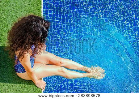Millennial Woman Relaxing By The Pool With Legs Dipped In Water. Health Care - Vitamin D Is Produced