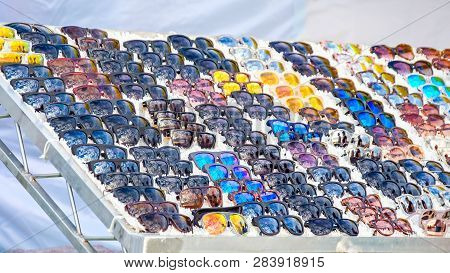 Colorful Variety Of Cheap Sunglasses Displayed On Market Stall For Sale