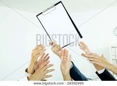 Obrázek několika lidských rukou se snaží získat papír z mužské ruky