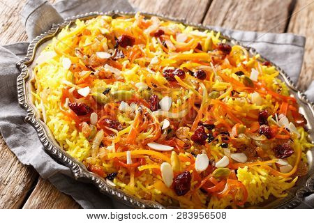 Saffron Pilaf With Dried Fruits, Carrots, Orange Zest, Spices And Nuts Closeup On A Plate. Horizonta