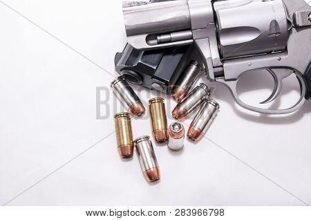 Two Handguns, A 40 Caliber Pistol And A 357 Magnum Revolver With 40 Caliber Bullets On A White Backg