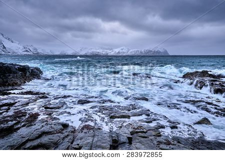 Waves of Norwegian sea crushing at rocky coast in fjord. Vikten, Lofoten islands, Norway