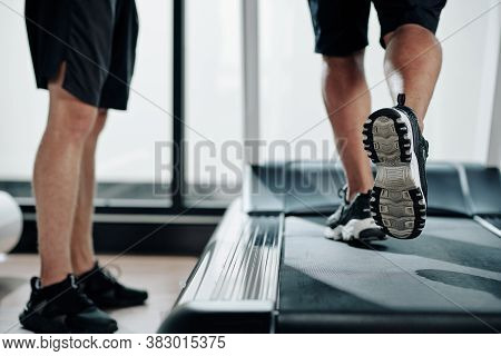 Low Section Of Fitness Trainer Standing Next To Treadmill And Contolling Mature Clinet Running To Wa