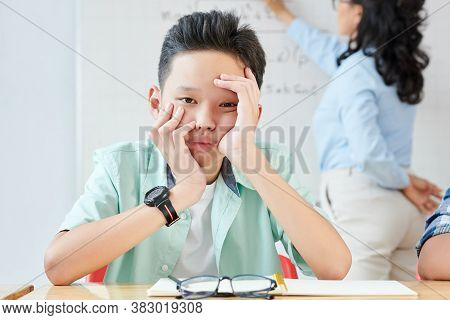 Bored Tired Vietnamese Shoolboy Sitting At Desk At Math Class