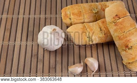 Garlic Bread Stuffed With Cheese Arranged On A Bamboo Mat With Garlic Around It On A Table, Selectiv