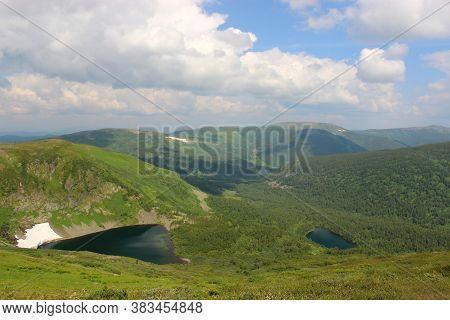 A Group Of Alpine Lakes Lying In A Hollow Surrounded By High Hills Covered With Snow.