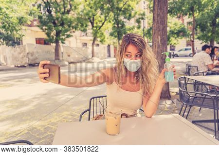Woman Wearing Protective Face Mask On Mobile Video Calling Friends In Coffee Shop In The New Normal