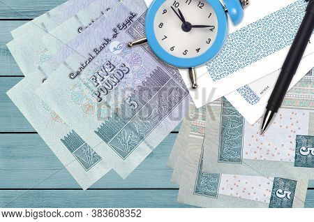 5 Egyptian Pounds Bills And Alarm Clock With Pen And Envelopes. Tax Season Concept, Payment Deadline