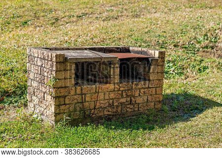 An Old Brick Barbecue In A Park With A Rusted Hotplate
