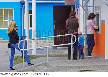Berezovka, Belarus - August 11, 2013: Woman Withdrawing Money From An Atm, Other Women Waiting In Li