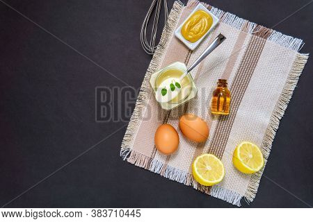 Homemade White Sauce Mayonnaise And Ingredients Eggs, Lemon Olive Oil On Black Background. Top View