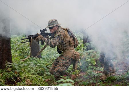 modern warfare soldier in action aiming at weapon  laser sight optics  in combat position while searching for a target in battle