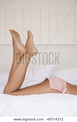 Sección baja de mujer joven en ropa interior en cama