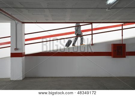 荷物とガレージ駐車場ランプを歩くビジネスマンの側ビュー低断面