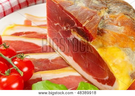 whole block and slices of parma ham with tomato cluster