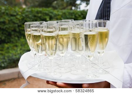 Waiter holding a tray of champagne outside