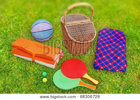 Picnic Basket,  Blanket,  Racquetball And Ball In The Grass