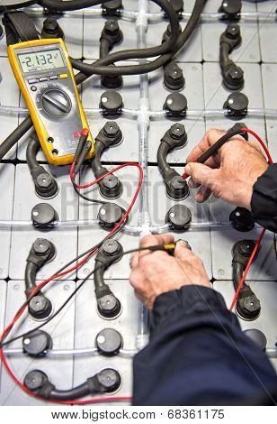 Mechanic, checking a large battery pack using a multimeter