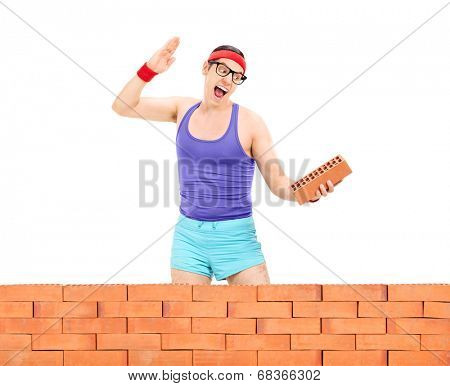 Man smashing a brick behind a brick wall isolated on white background