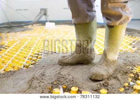Plasterer at indoor concrete cement floor topping with float