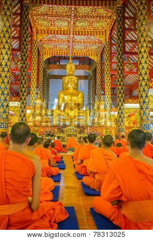 CHIANG MAI, THAILAND - NOVEMBER 18, 2014: Young buddhist monks praying in front of the Buddha image in Wat Suan Dok temple in Chiang Mai, Thailand on 18 November, 2014