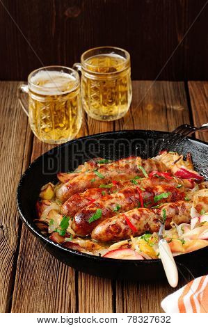 Sausages Fried In Cast Iron Skillet With Two Beer Mugs
