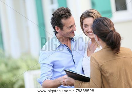 Couple meeting real-estate agent outside new property