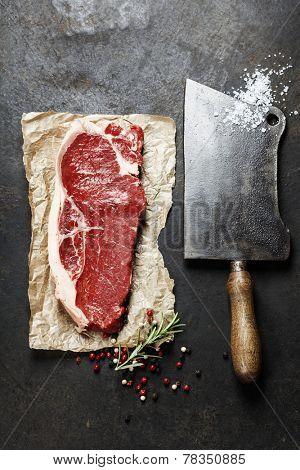 vintage cleaver and raw beef steak on dark background