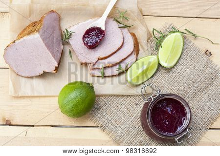 Home made organic cherry jam confiture, smoked meat and lime on a wooden table