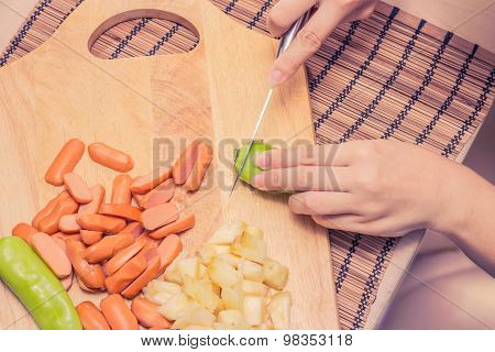 Preparing sausage and vegetables woman hands vintage tone.