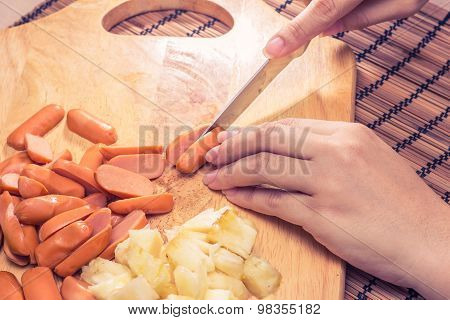Preparing sausage and vegetables woman hands vintage tone.