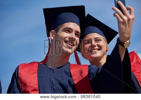Capturing a happy moment.Students group  college graduates in graduation gowns  and making selfie photo