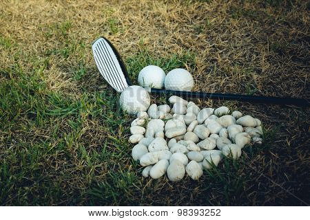 Golf Ball And Golf Club Beside Mini Stone On The Grass