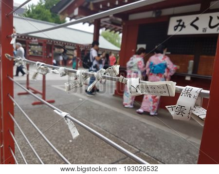 TOKYO, JAPAN- May 2017 O-mikuji (fortune prediction) or reading a strips of paper and two unidentified women wearing traditional kimono at Sensōji (Asakusa Kannon Temple)