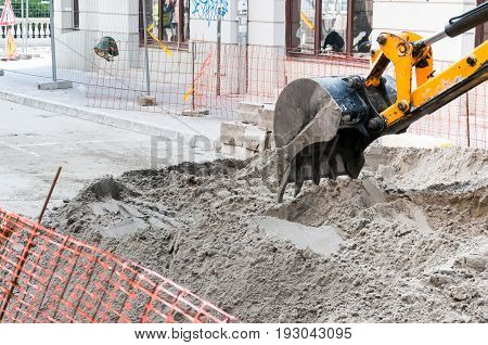 Excavator. Close up of a construction site excavator. Excavator machinery on construction site repair old road on the street.